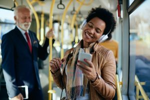 Happy African American woman listening music while commuting by public transport