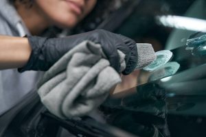 Auto shop worker wiping windscreen with microfiber cloth